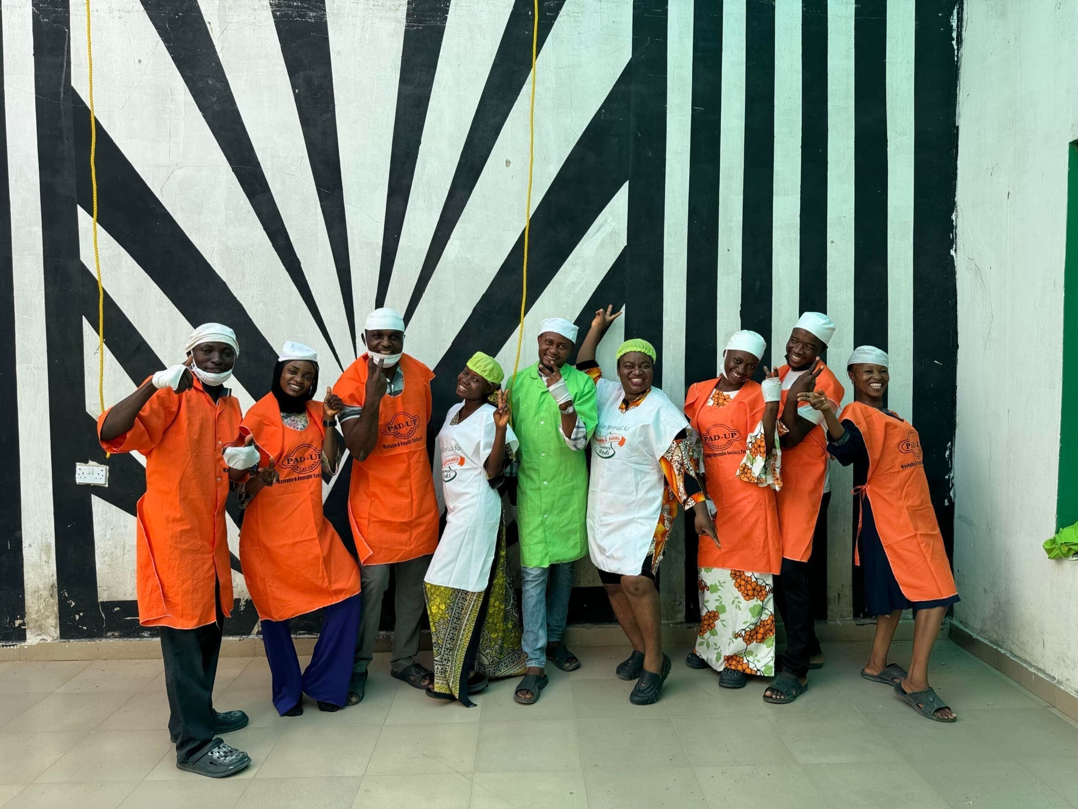 Pad-Up production team in branded aprons and hairnets in front of a painted mural